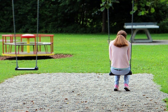 A downcast teacher sits alone on a swing pgce