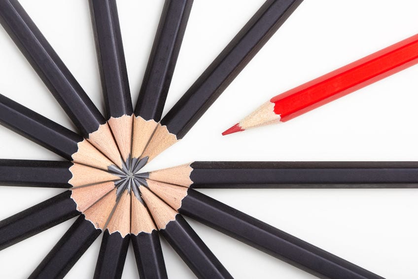 A red pencil standing out among grey pencils signifying difference