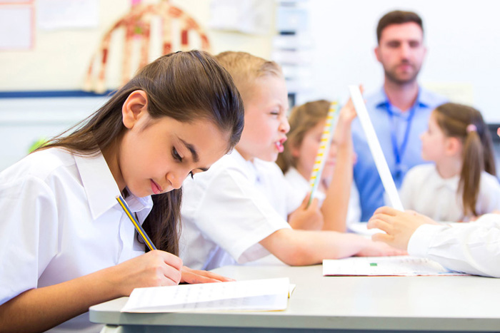 Primary school girl writing in her planner during class to support learning and organisation.